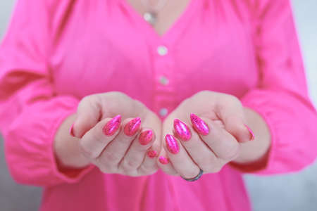 Female hands with long nails and neon pink nail polishの写真素材