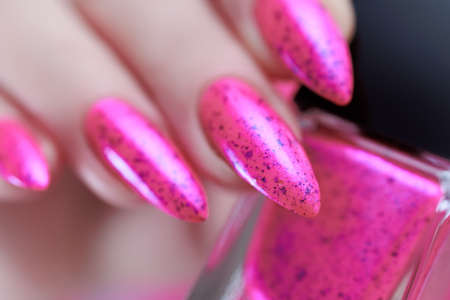 Female hands with long nails and neon pink nail polish