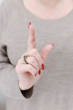 Female hand with long nails and a bright red manicure holds a bottle of nail polishの写真素材