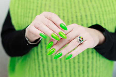 Female hand with long nails and neon green manicure with bottles of nail polishの写真素材