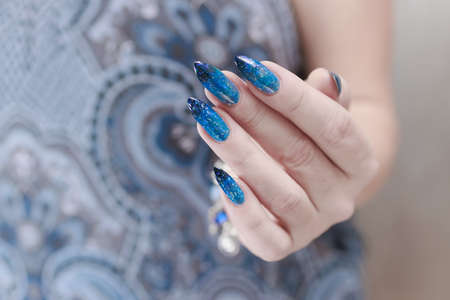 Female hands with long nails with bright blue nail polishの写真素材