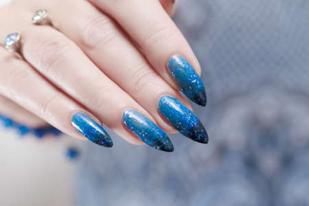 Female hands with long nails with bright blue nail polishの写真素材