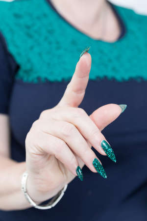 Female hand with long nails and neon green manicure with bottles of nail polishの写真素材