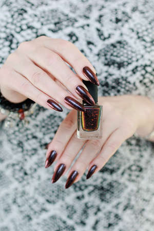 Female hands with long nails and black and red nail polishの写真素材