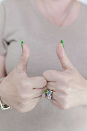 Female hand with long nails and neon green manicure with bottles of nail polish