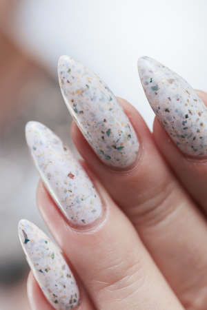 beautiful female hands with long nails light white manicure and a bottle of nail polish