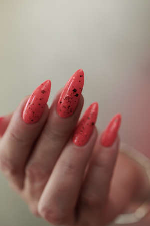 Female hands with long nails and neon pink coral nail polish