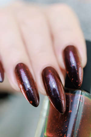 Female hands with long nails and black and red nail polish