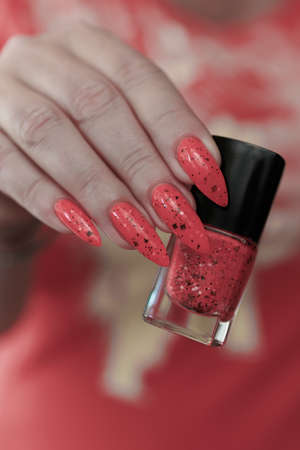 Female hands with long nails and neon pink coral nail polishの写真素材