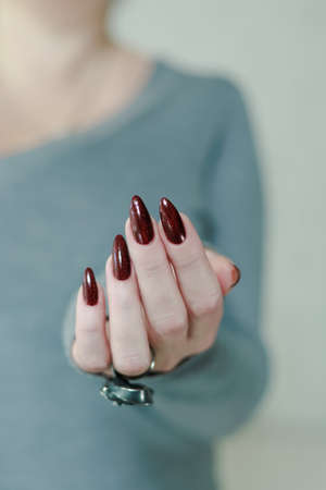 Female hands with long nails and dark red nail polishの写真素材