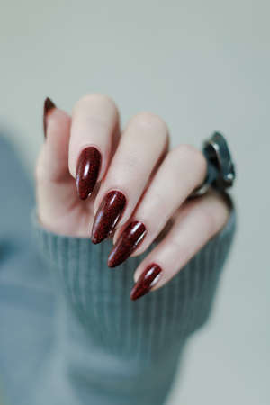 Female hands with long nails and dark red nail polish