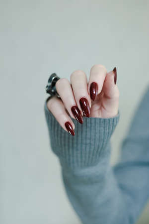 Female hands with long nails and dark red nail polishの写真素材
