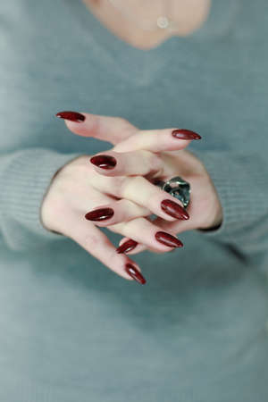 Female hands with long nails and dark red nail polish