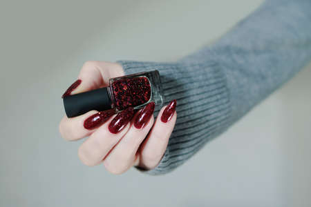 Female hands with long nails and dark red nail polish