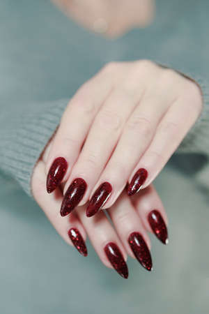 Female hands with long nails and dark red nail polishの写真素材