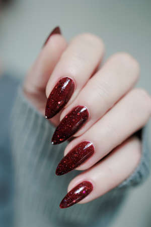 Female hands with long nails and dark red nail polish