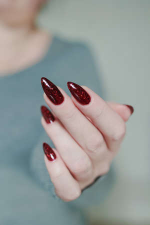 Female hands with long nails and dark red nail polishの写真素材