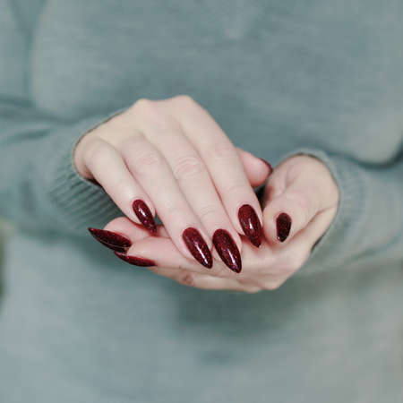 Female hands with long nails and dark red nail polish