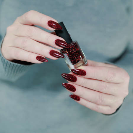 Female hands with long nails and dark red nail polish