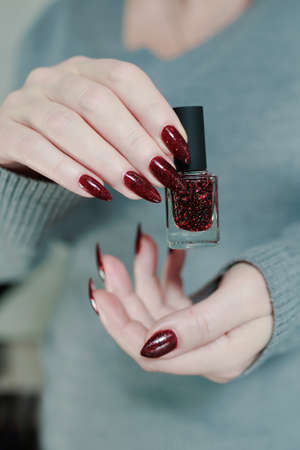 Female hands with long nails and dark red nail polish