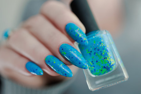Woman's beautiful hand with long nails and light blue manicure with bottles of nail polish