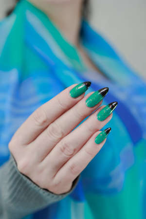 Female hand with long nails and green-black thermo french nail polishの写真素材