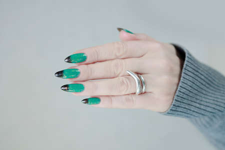 Female hand with long nails and green-black thermo french nail polishの写真素材
