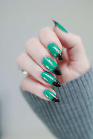 Female hand with long nails and green-black thermo french nail polishの写真素材