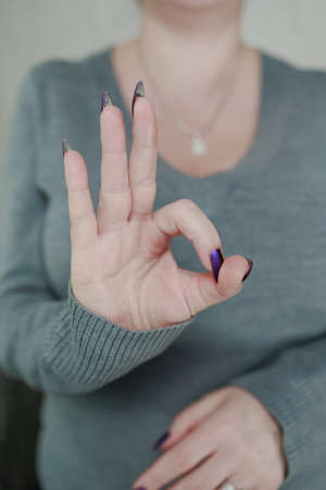 Female hand with long nails and purple plum manicure holds a bottle of nail polish
