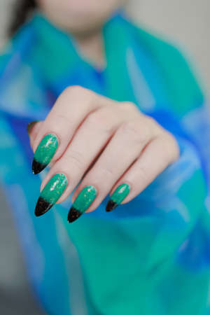 Female hand with long nails and green-black thermo french nail polish