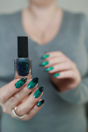 Female hand with long nails and green-black thermo french nail polish