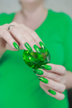 Female hands with long nails and green and black thermo manicure with bottles of nail polishの写真素材