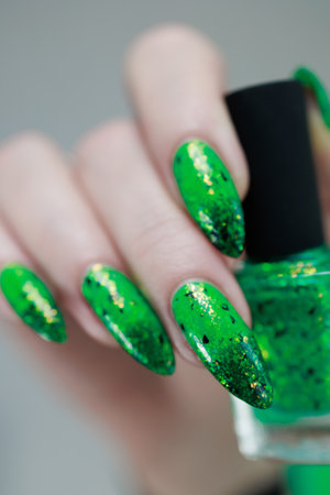 Female hands with long nails and green and black thermo manicure with bottles of nail polish