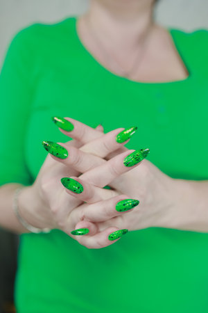 Female hands with long nails and green and black thermo manicure with bottles of nail polishの写真素材