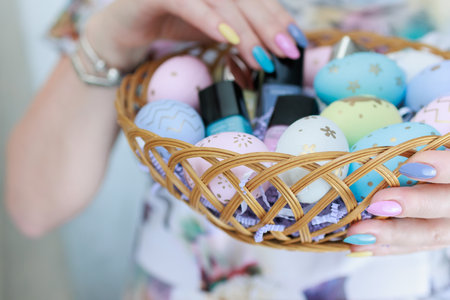 Women's hands with multi-colored manicure hold Easter eggs. Light yellow, blue and pink color.の写真素材