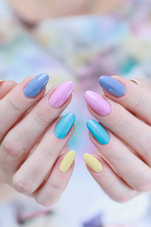 Multicolored manicure, female hands with colored nails, nail polishes, yellow, blue and pink colors.の写真素材