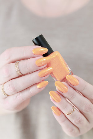 Female hand with long nails and a yellow orange nail polish