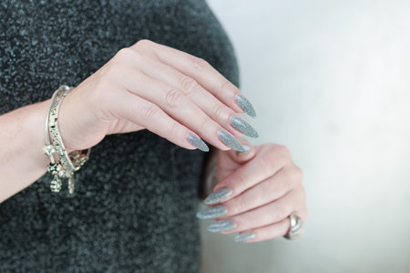 Female hand with long nails and a white gray silver manicureの写真素材