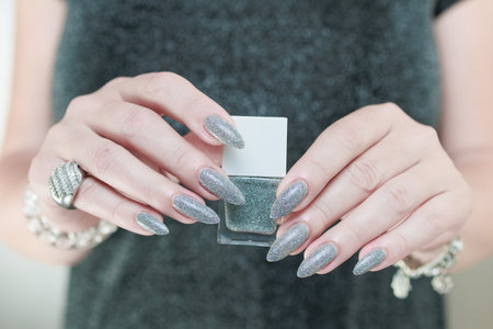 Female hand with long nails and a white gray silver manicureの写真素材