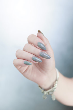 Female hand with long nails and a white gray silver manicureの写真素材
