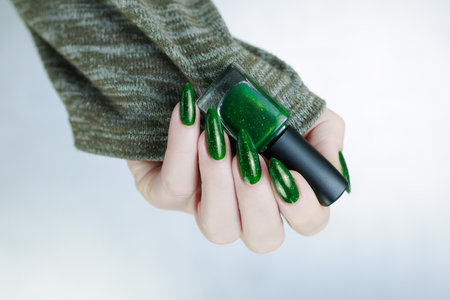 Woman's hand with long nails and green nail polishの写真素材