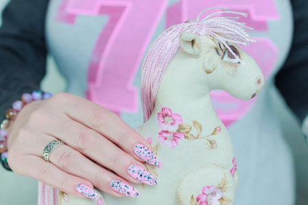 Women's hands hold a toy pink horseの写真素材
