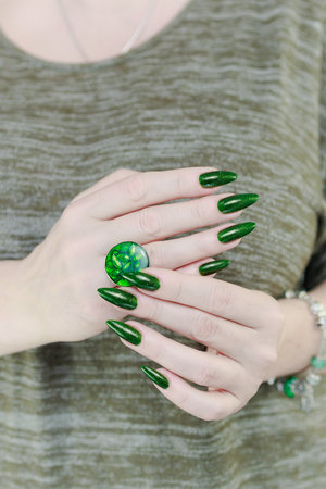 Woman's hand with long nails and green nail polishの写真素材