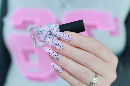 Woman hand with long nails manicure and light pink nail polish