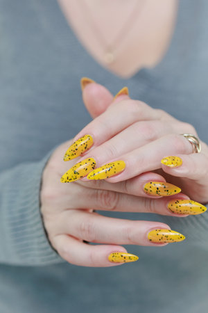 Female beautiful hand with long nails and a yellow nail polishの写真素材