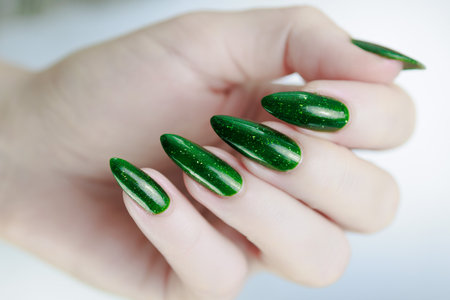 Woman's hand with long nails and green nail polish
