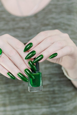 Woman's hand with long nails and green nail polishの写真素材
