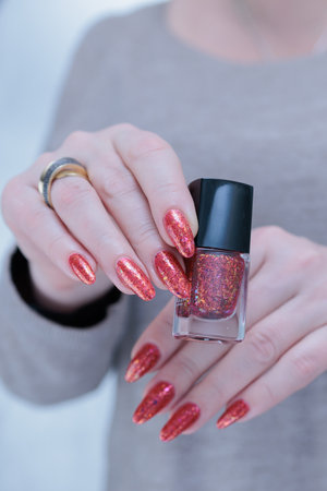 Female hand with long nails and a bright orange red manicure