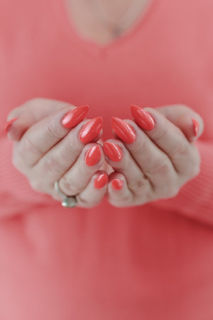 Woman hand with long nails and light orange coral neon manicure