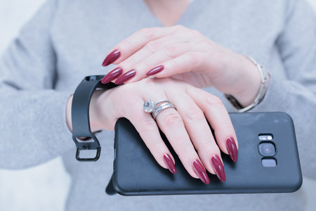 Woman's hands holding a smartphone and Digital Watch